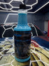 Blue bottle of car care product on a reflective surface with a car in the background