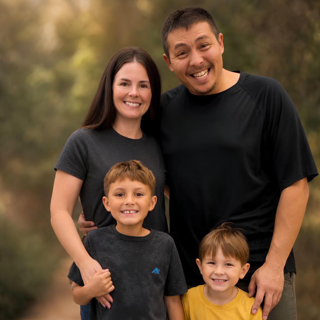 Family of four posing together outdoors with a natural background