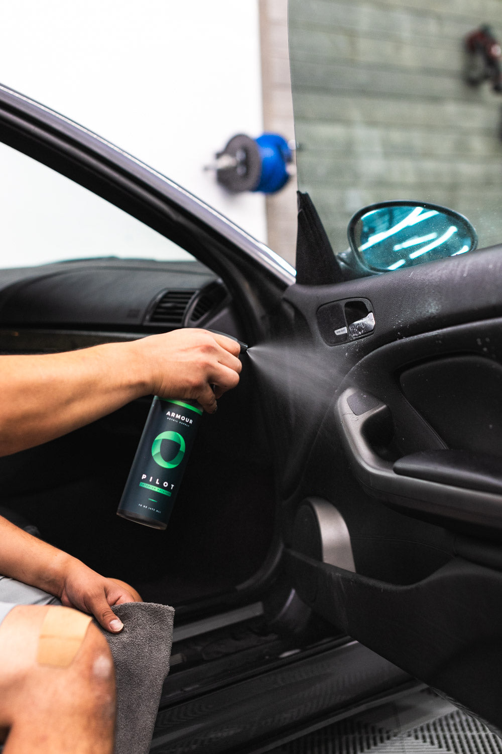 PILOT Interior Detailer being sprayed onto a vehicle's interior door panel.