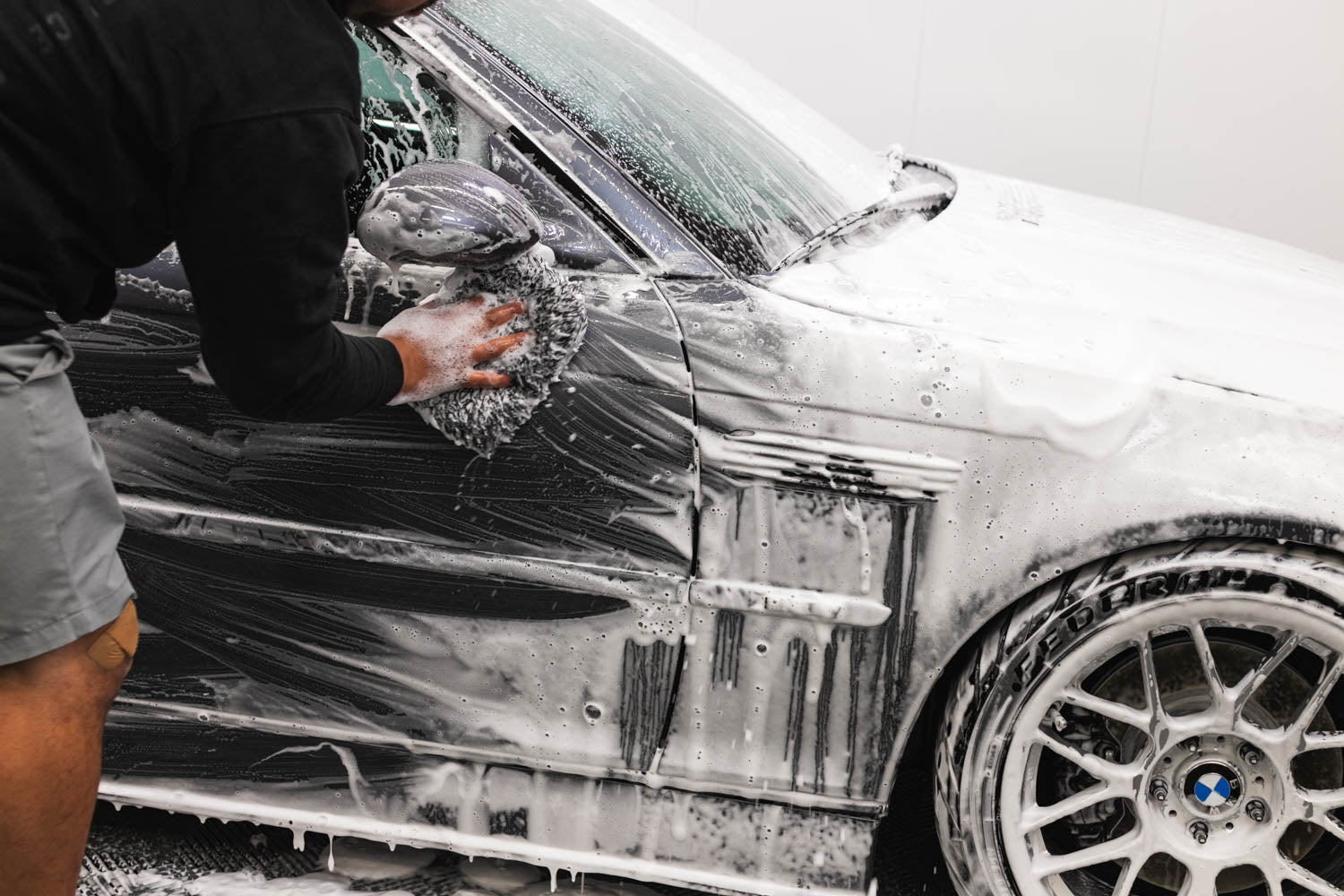 A foam-covered car being contact washed with wash media.