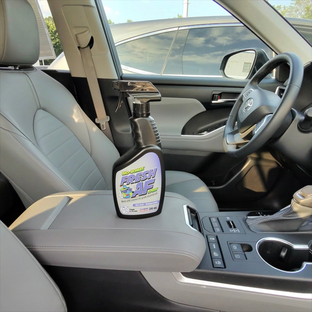 That Detail Shop Bio-Bombs Fresh AF air freshener spray bottle sitting on the center console of a clean car interior.