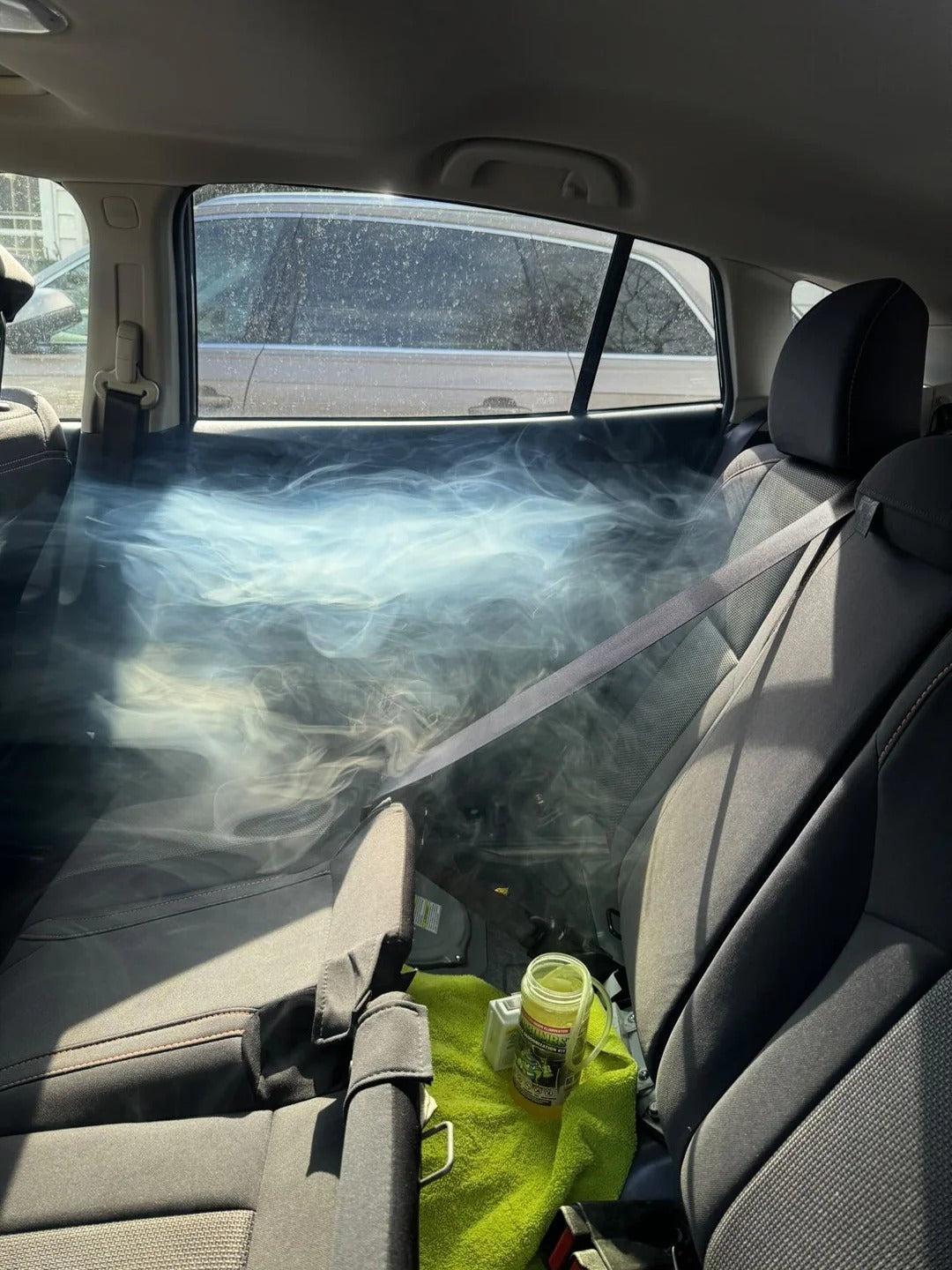 That Detail Shop Bio-Bombs vehicle deodorizer fogging the interior of a car. Smoke-like vapor fills the back seat area.