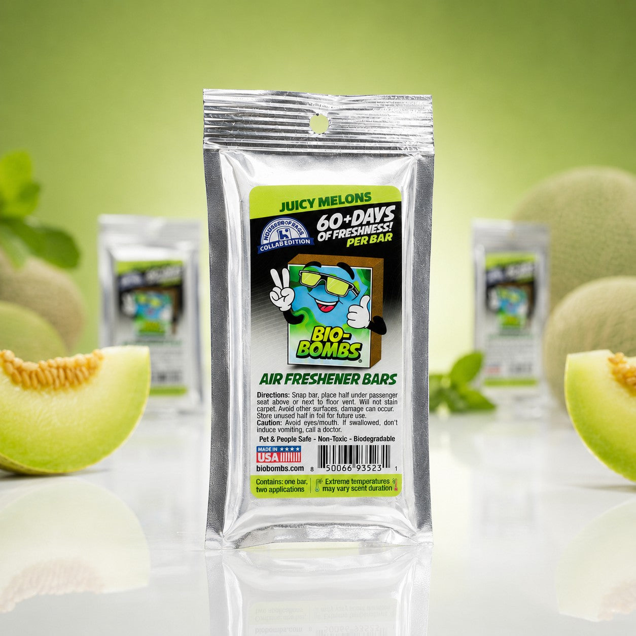 That Detail Shop Bio-Bombs Juicy Melons air freshener bar in silver packaging with a cartoon earth character giving peace signs.
