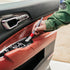 That Detail Shop detailing brush cleaning car interior door panel with red leather and black trim.