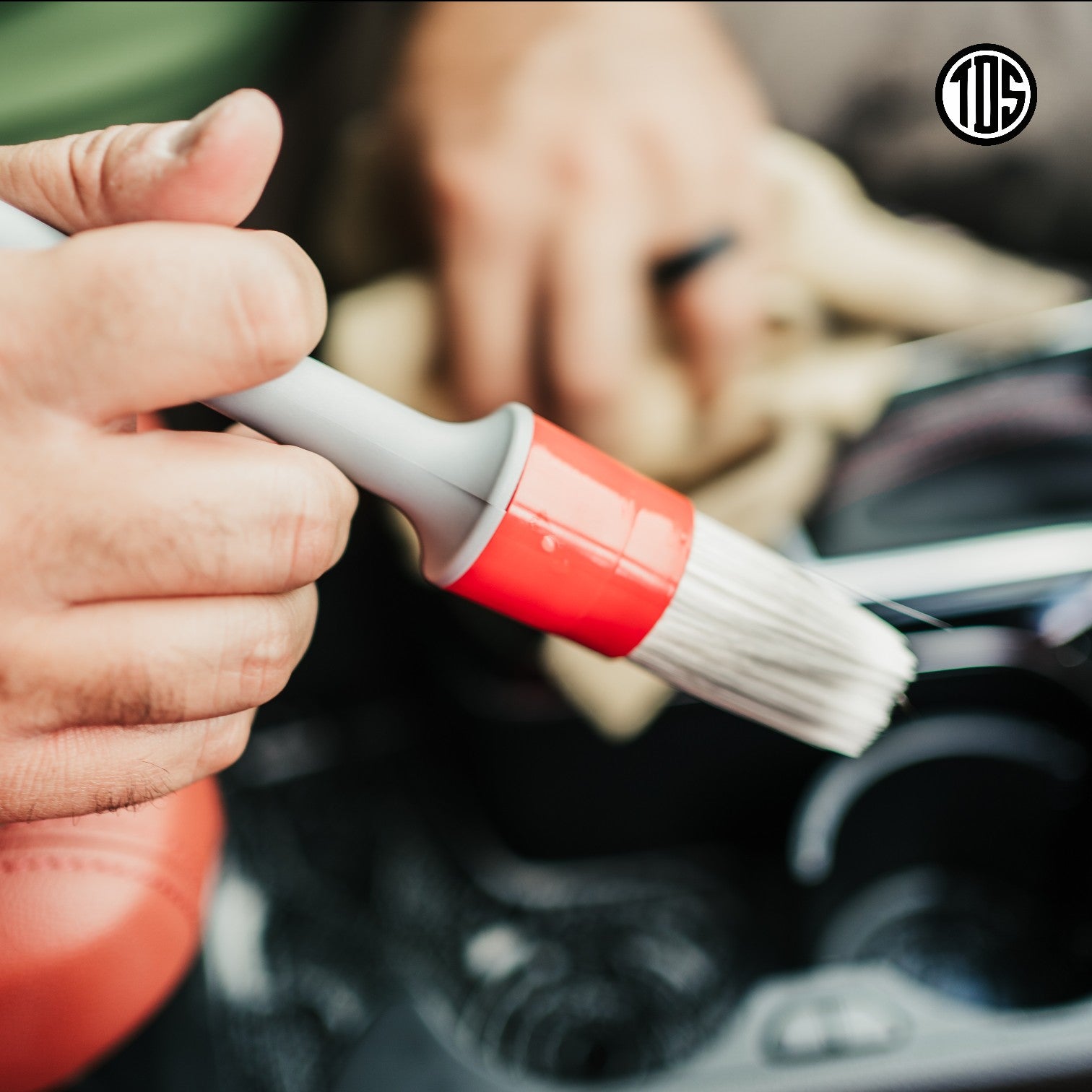 That Detail Shop detailing brush with white bristles and red ferrule cleaning car interior.