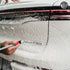 That Detail Shop exterior detailing brush cleaning the 'LIMITED' emblem on a white car covered in foam.