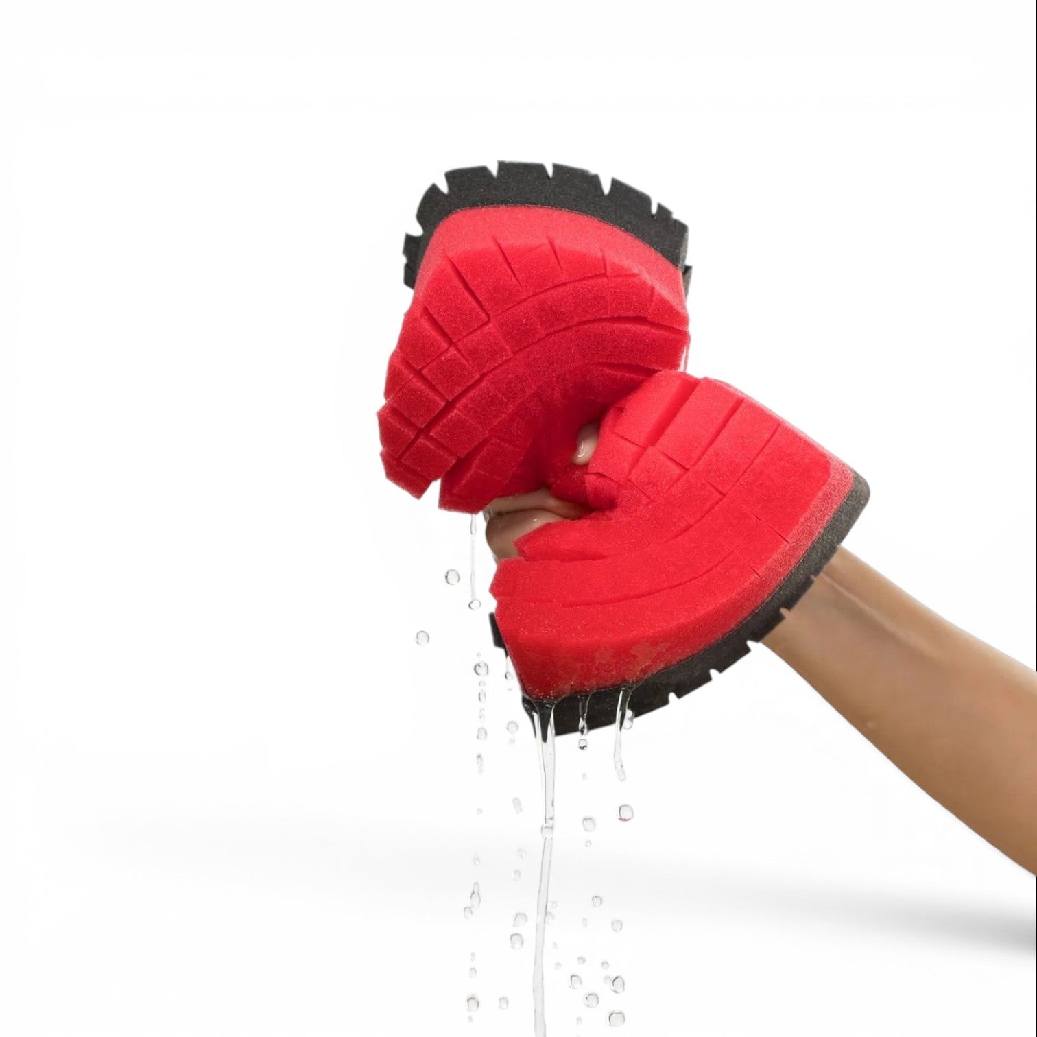 That Detail Shop Legacy Sponge, a large red car wash sponge with black trim, being squeezed to release water.