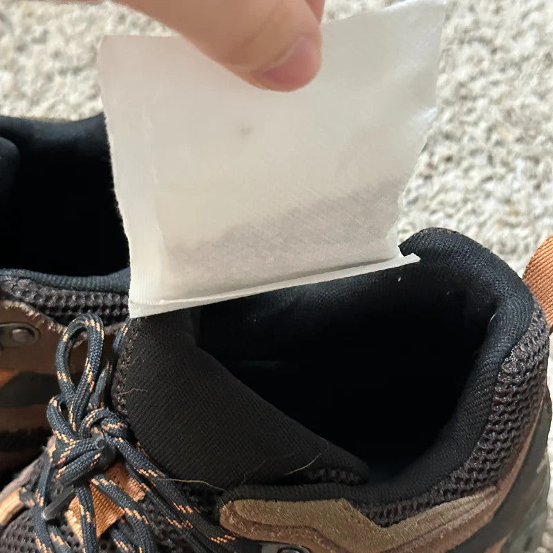 That Detail Shop Odor Control Granule Sachets being placed into a brown and black hiking boot.