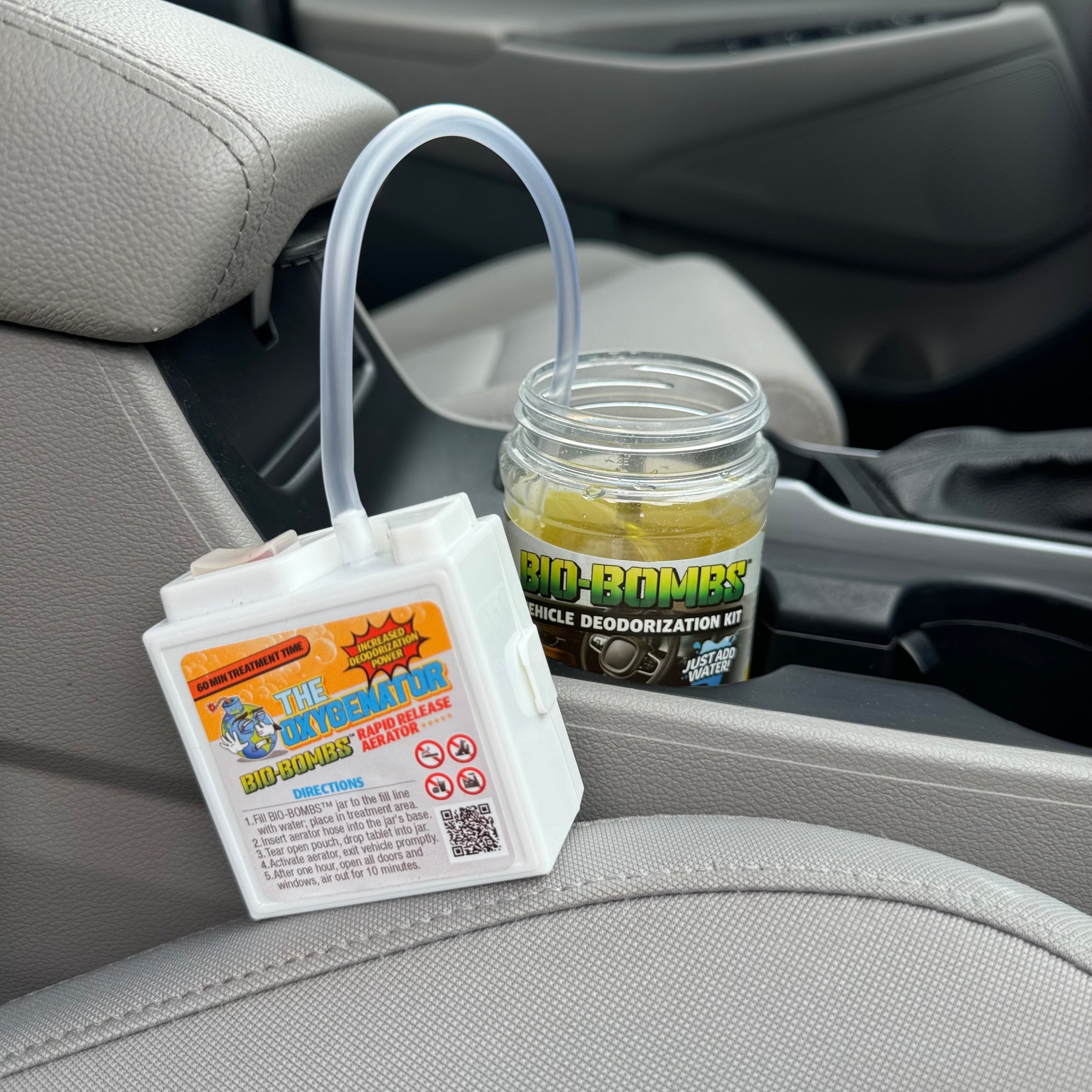 That Detail Shop Oxygenator Aerator device connected to a Bio-Bombs VDK jar in a car interior for odor treatment.