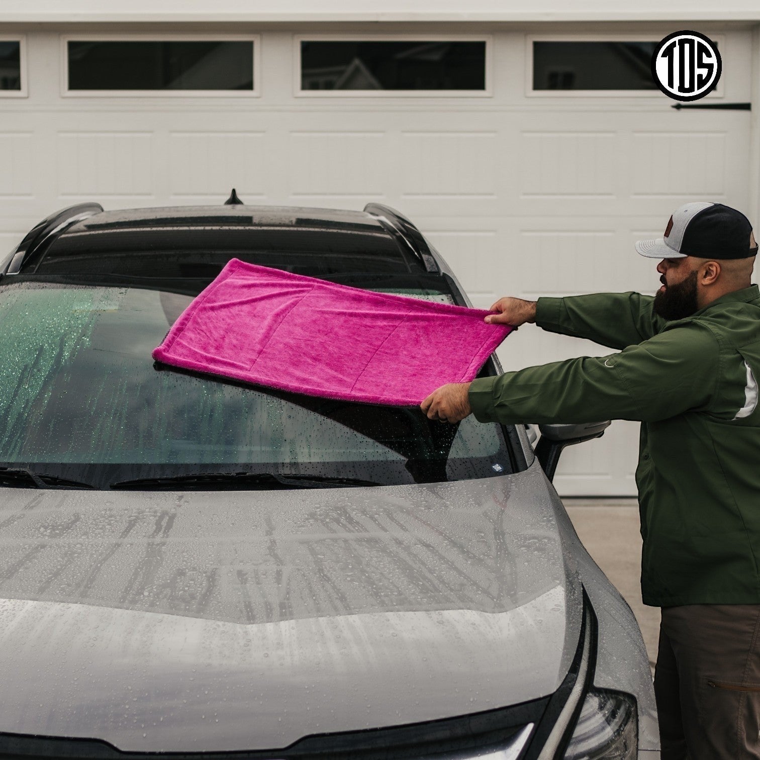 That Detail Shop pink and gray microfiber drying towel being used on a car windshield.