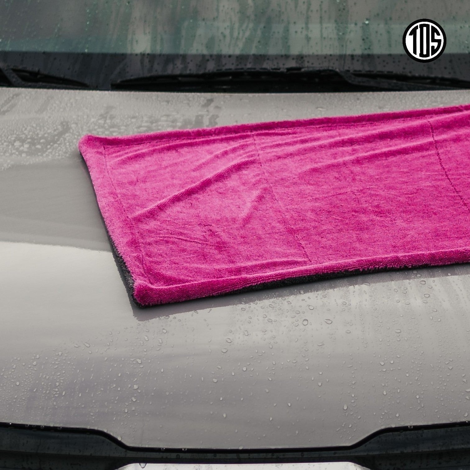 That Detail Shop pink and gray 1400 GSM microfiber drying towel with twisted loops on a wet car hood.