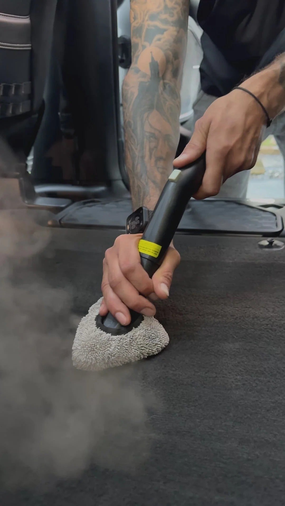 That Detail Shop technician steaming car interior carpet for deep cleaning and odor treatment.