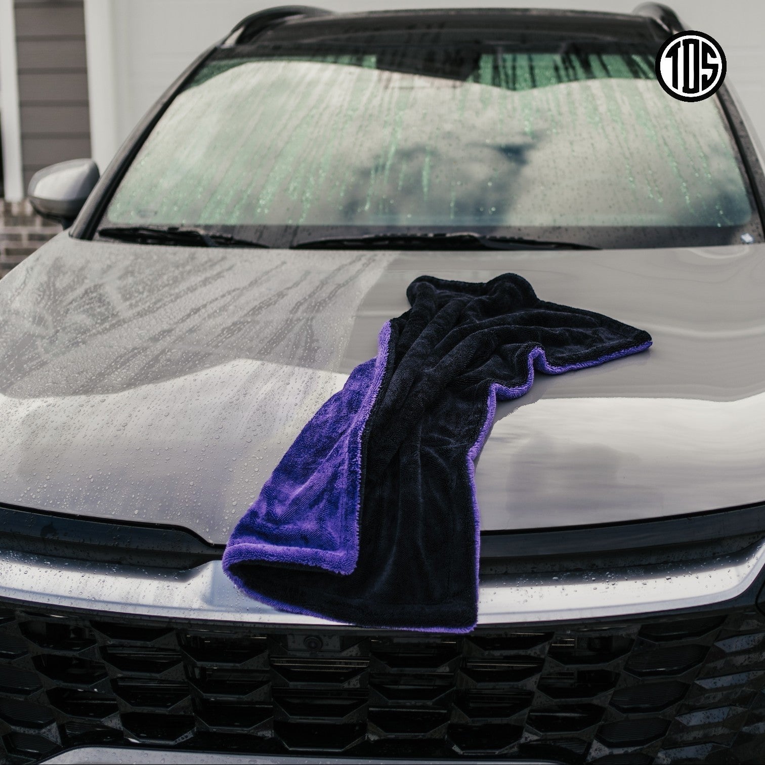 That Detail Shop TDS 1600 DT drying towel in purple and black microfiber on a wet car hood.