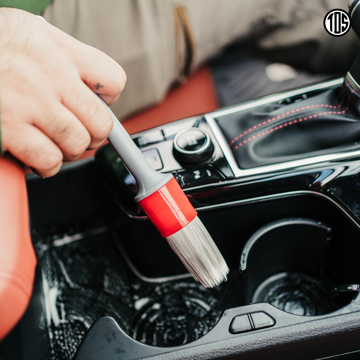 That Detail Shop interior detailing brush with soft synthetic bristles and red handle cleaning car console crevices.