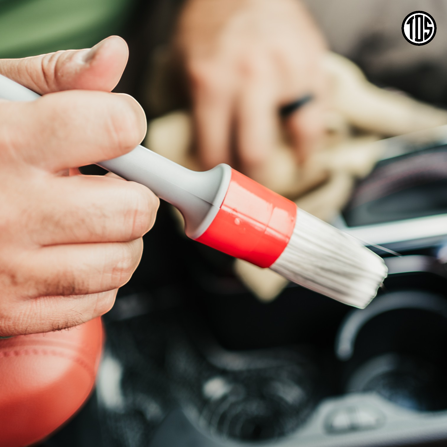 That Detail Shop interior detailing brush with soft white bristles and a red and grey handle, used for cleaning car vents and crevices.